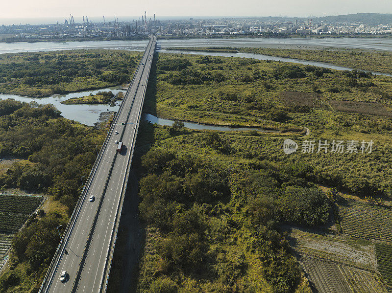 汽车在高速公路路口行驶的鸟瞰图。桥梁道路与绿色花园和树木连接的建筑概念