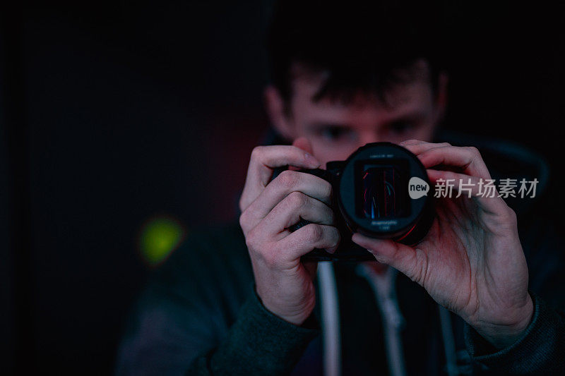 摄影师在室内霓虹灯色，人在专业相机设备上用变形镜头用紫色和粉色光拍摄。摄影师作为操作员，电影效果，生活方式概念摄影与选择性聚焦。