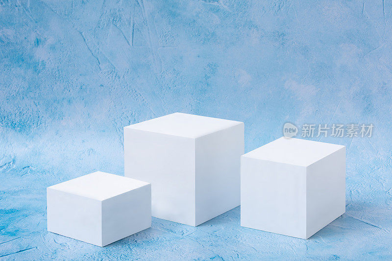 白色立方体美容化妆品新产品讲台上的蓝色背景。促销、销售、展示。几何形状。对象的位置。
