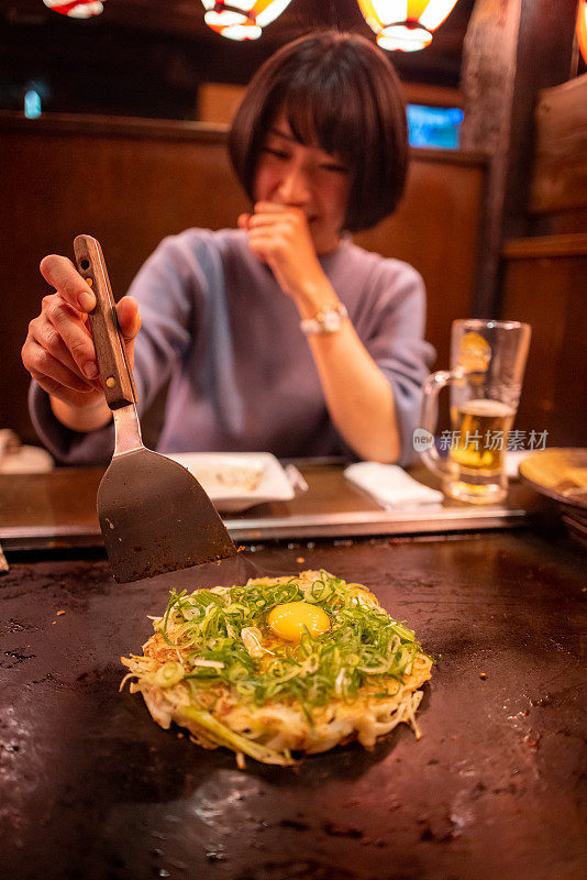 年轻女子在日本居酒屋酒吧烹饪御明烧