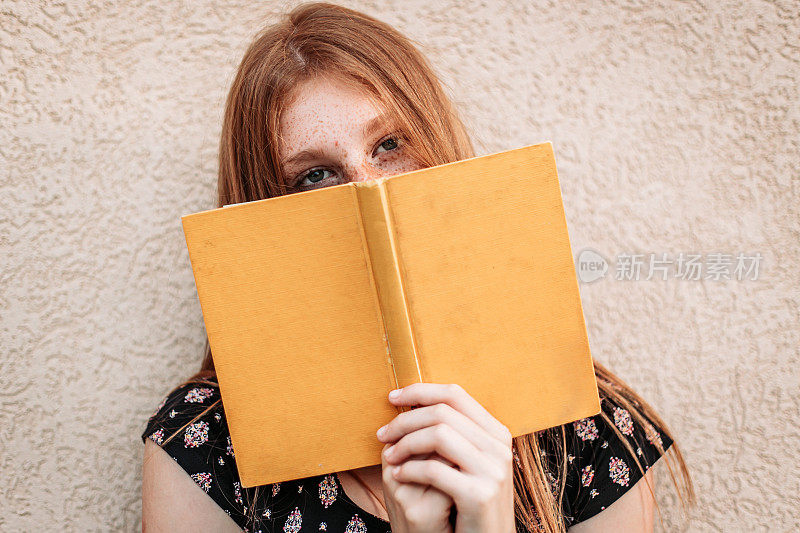 少年姜色女学生手里拿着一本书，脸上藏着一本书