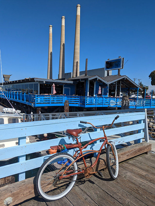 2023年4月，加州莫罗湾的莫罗岩石和渔港码头，码头上有一辆旧自行车，背景是烟囱