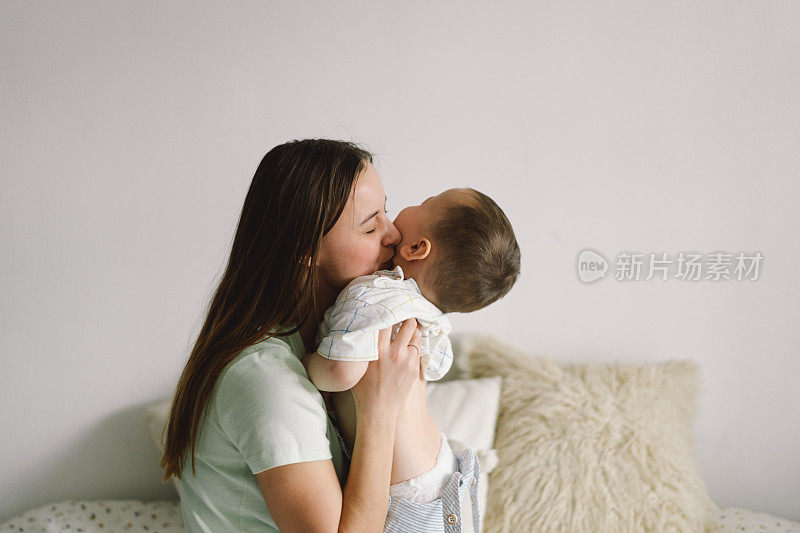 一个小男孩和妈妈躺在床上的家庭肖像。生活方式