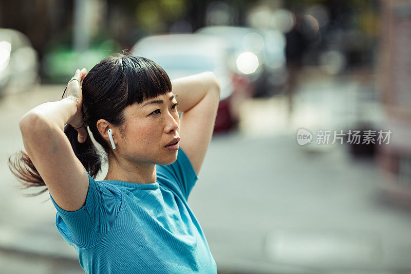 一名年轻的日本女子在城市里慢跑前正在扎头发