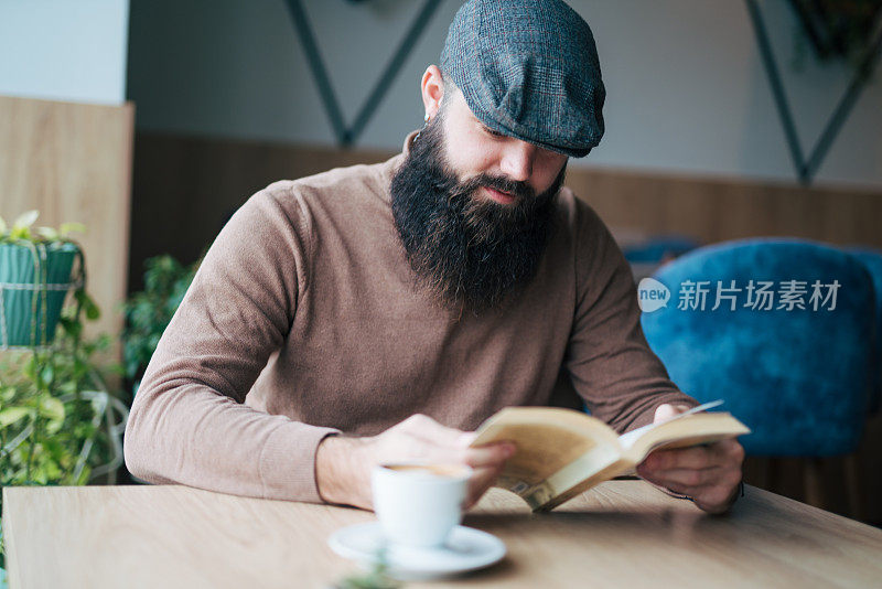 年轻英俊的男子在一家现代化的咖啡馆餐厅看书