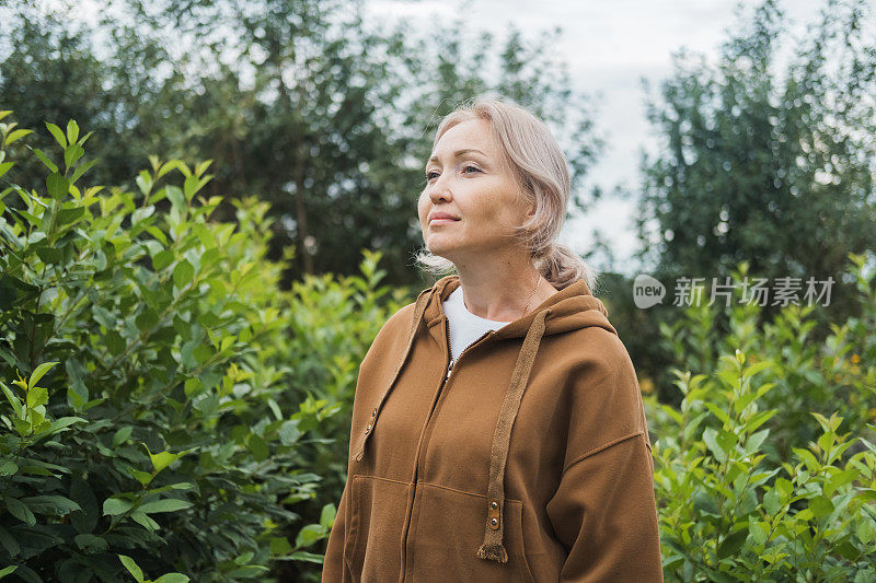 一个放松的白人妇女在绿色的森林里呼吸新鲜空气的肖像。