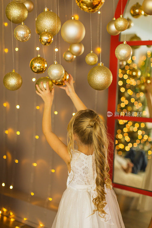 穿白裙子的金发女孩在玩圣诞球。