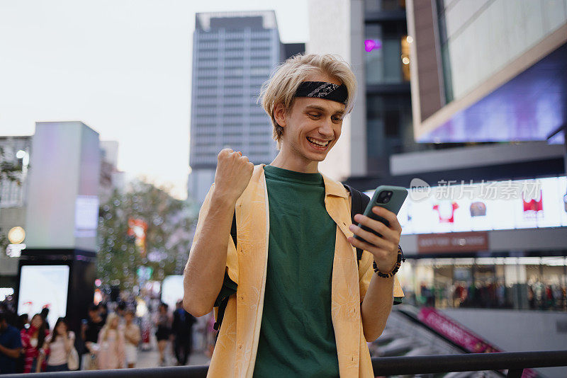 快乐的年轻人在城市里通过手机读着好消息。