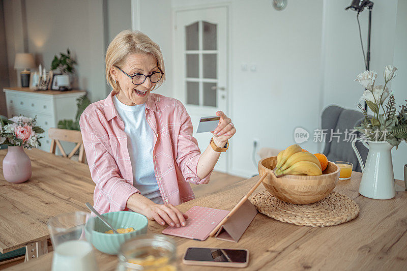 白人老年妇女持有信用卡，在网上购物