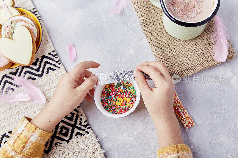 孩子们用手在甜美的可可和粉彩饼干中点缀着撒有糖屑的饼干，享受复活节的快乐