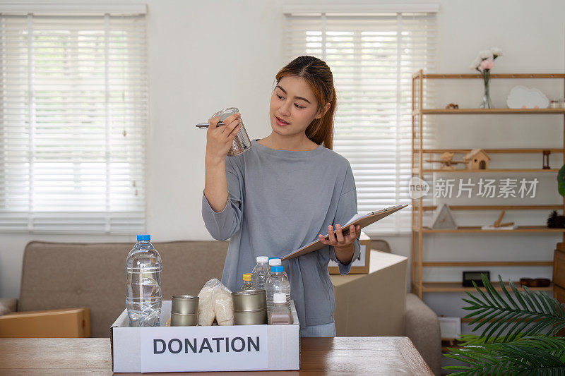 亚洲女志工将食物装在纸板箱里，捐赠给有需要的人