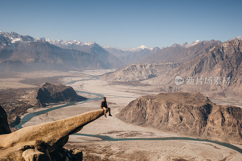 男旅行者坐在马苏尔岩石上，看着印度河的风景