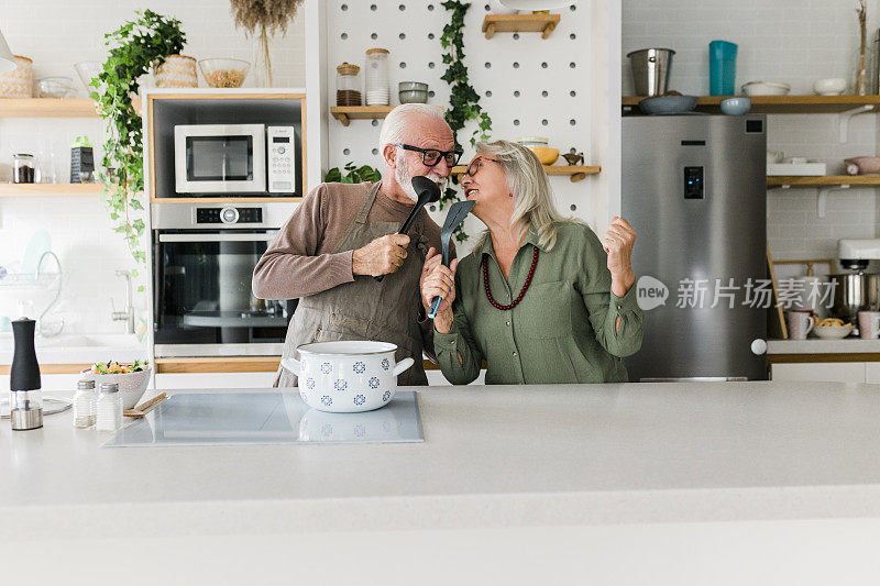 老夫妇一起在厨房做饭。退休后的生活方式，休闲和在家消磨时间。
