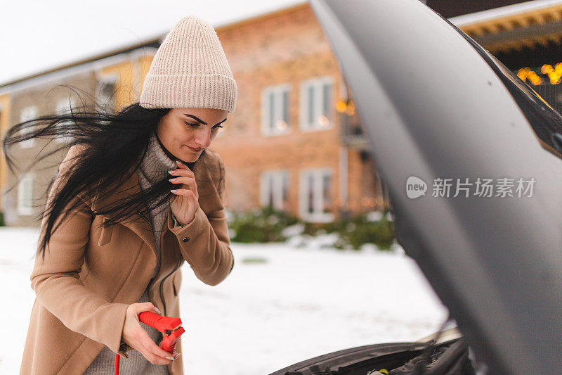 一名年轻女子试图弄清楚如何在冬天启动她的车