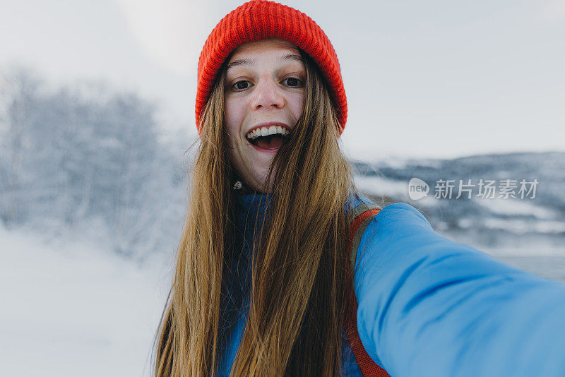 戴着红帽子的快乐女子在挪威的冬季森林里自拍