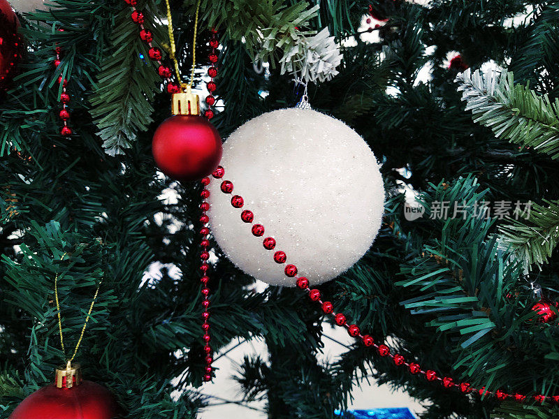 有装饰品、圣诞球和玩具的圣诞树。红白相间的挂饰。大大小小的小球，红红的珠子。