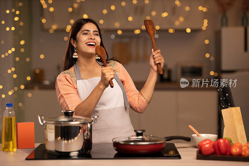 一个年轻女子的肖像烹饪食物在厨房的股票照片