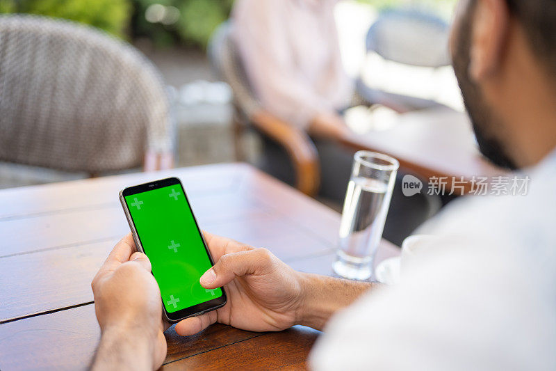 男子在咖啡馆使用绿屏智能手机