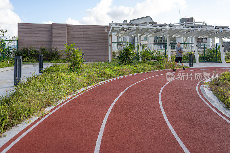 一个胖子正在运动场上跑步和锻炼