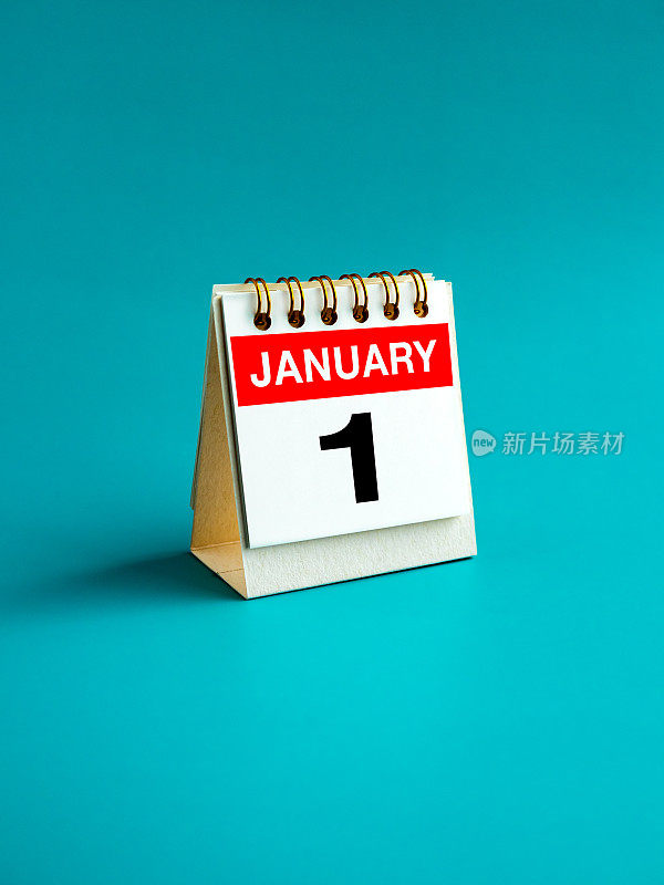 1月1日的大数字在书桌上折叠日历站在浅蓝色背景孤立。每月和每年的第一天，垂直。1月新年佳节快乐，极简风格。