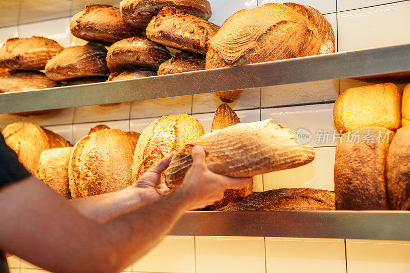 面目全非的面包房工人把刚烤好的面包放在展示架上