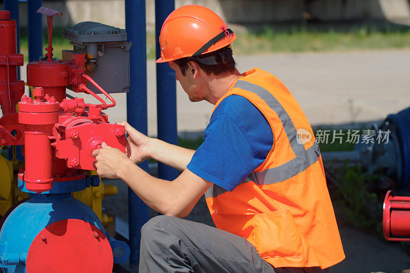 工业气体设备的维护。夏日，戴安全帽的工人在仓库检查设备