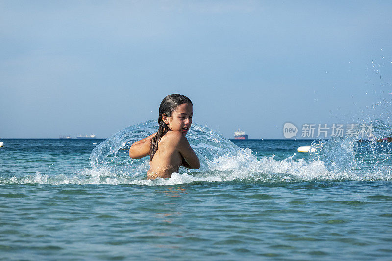 他用手在海里泼水。一个夏天的早晨。忒涅多斯岛。爱琴海北部，12岁的帅哥。长头发的