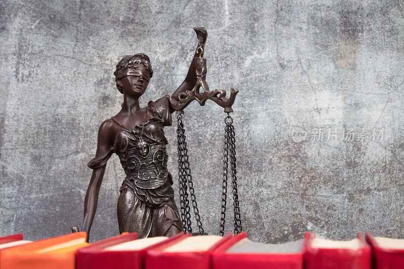 法律概念-打开法律书秤，法庭或执法办公室桌子上的忒弥斯雕像。