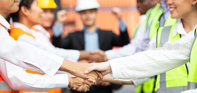 一群成功的物流工程师在集装箱仓库握手签订业务协议或公司合作。团队合作及伙伴概念