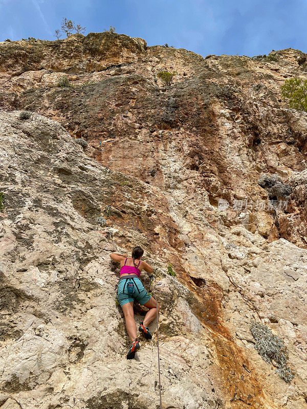 低角度视角:年轻的女运动员在美丽的克罗地亚海边带领攀岩