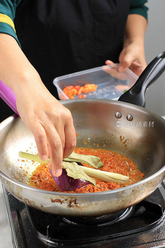 将干月桂叶(清晨萨拉姆)放入锅中，加入辛辣香料，由厨房的女家庭厨师一步一步地烹饪。印尼传统麻辣配方的制作过程