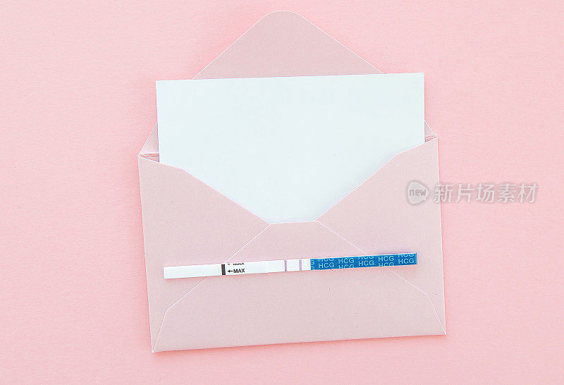 阳性妊娠试验在粉红色信封粉红色背景，明信片与文字的地方，怀孕的概念。