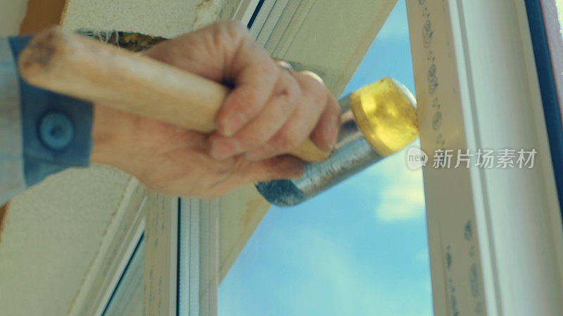 一个工人用橡胶锤敲窗户的手的底图