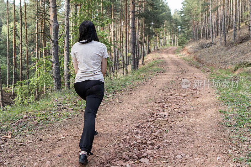 快乐的女跑步者正在森林里阳光明媚的小路上享受慢跑或越野跑。