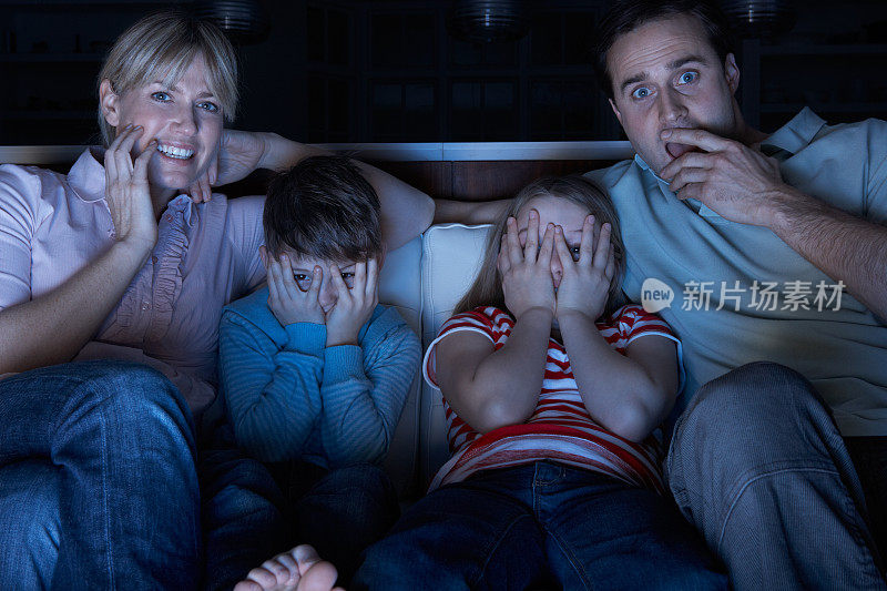 家人一起坐在沙发上看恐怖的电视节目