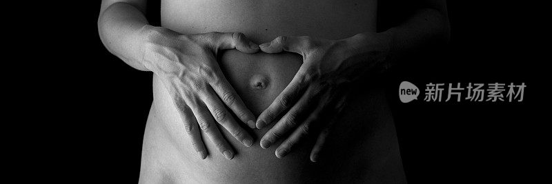 女人的手在她怀孕的肚子上做心形