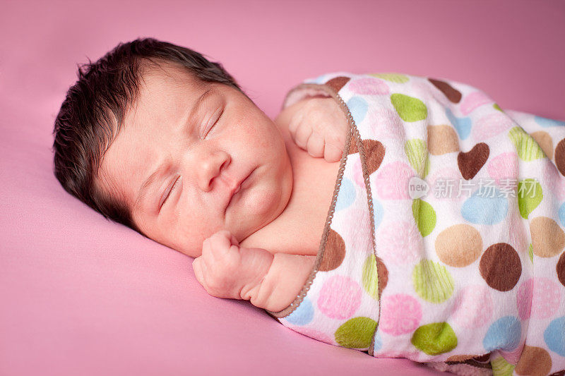 在毯子里睡着的新生女婴的彩色图像