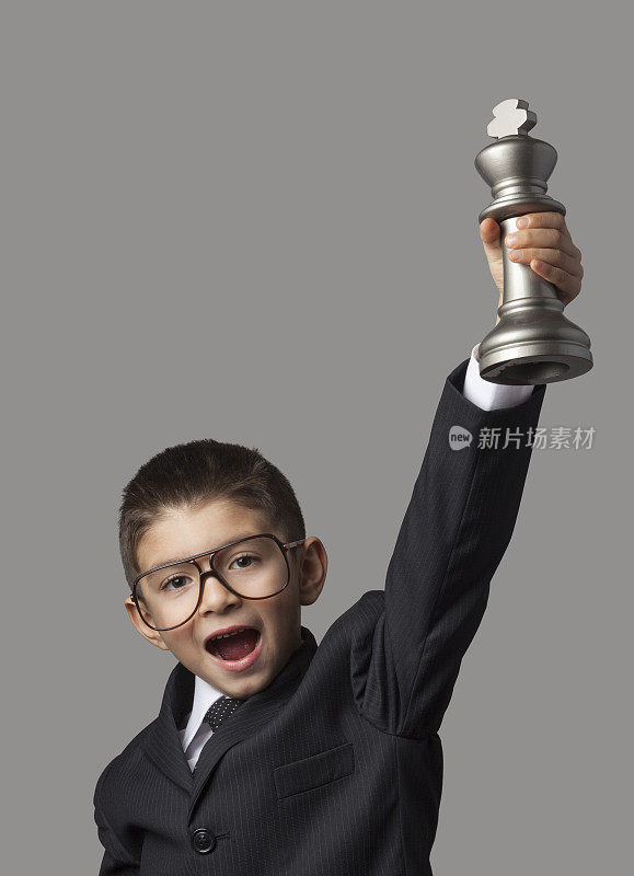 聪明的小男孩举起象棋冠军奖杯