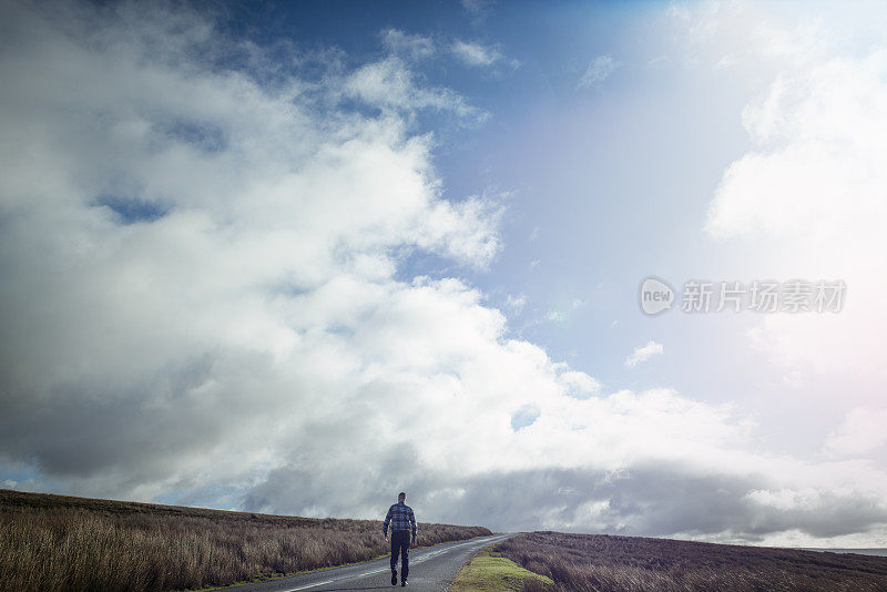 一个人走在开阔的乡村道路上