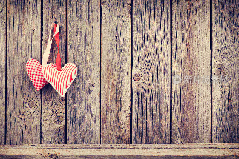两颗情人节的心挂在质朴的木墙上