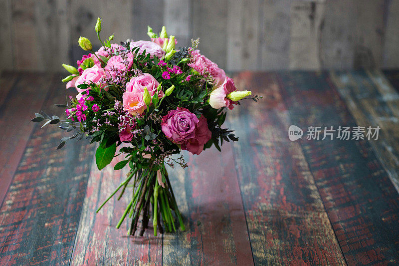 带有粉色玫瑰和洋桔梗花的乡村婚礼花束。