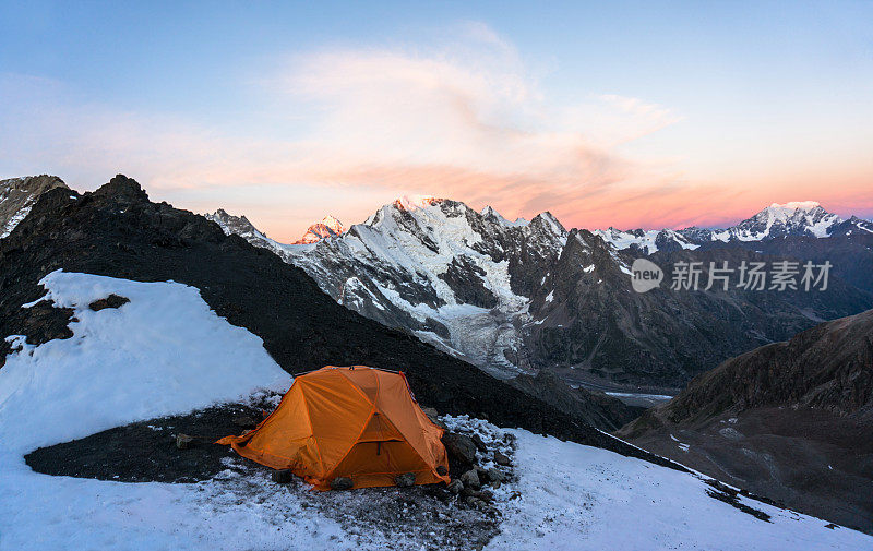 孤独的橘黄色帐篷攀登者在高山上