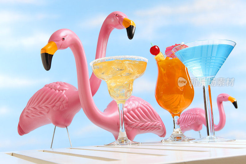 在三只粉红色火烈鸟面前喝着热带饮料