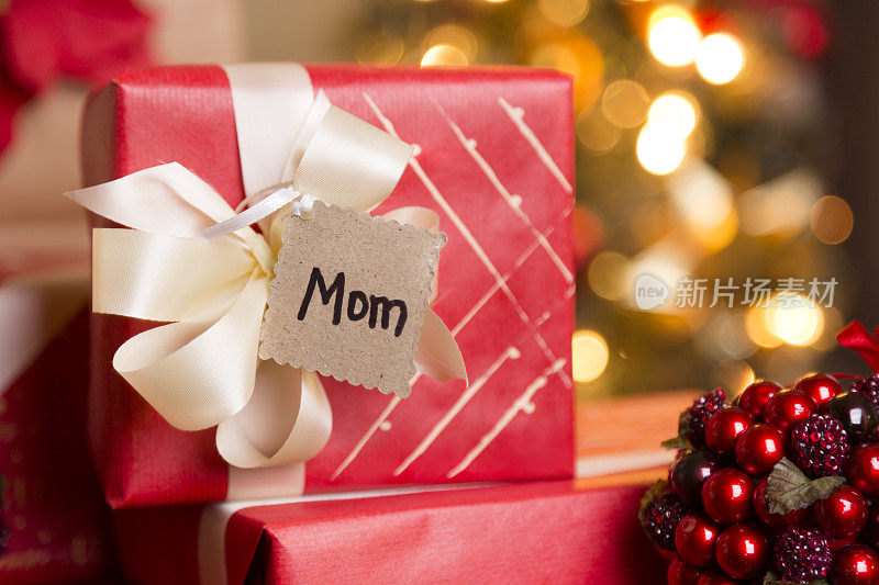 圣诞节:给妈妈包装精美的节日礼物。树在后台。