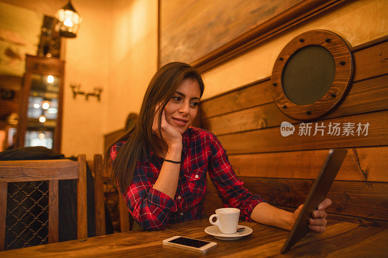 微笑的女人在咖啡馆里看电子书。