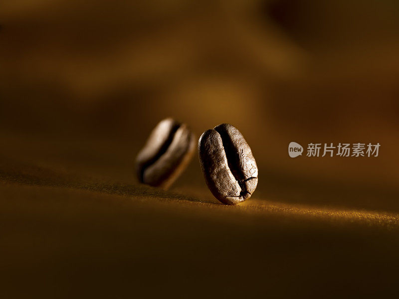 两颗咖啡豆落在棕色的表面上