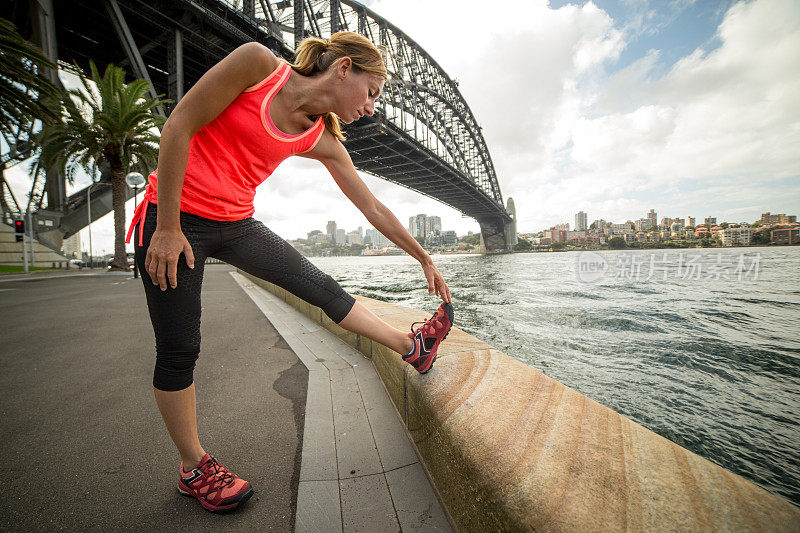年轻女子在悉尼海港大桥边伸展身体