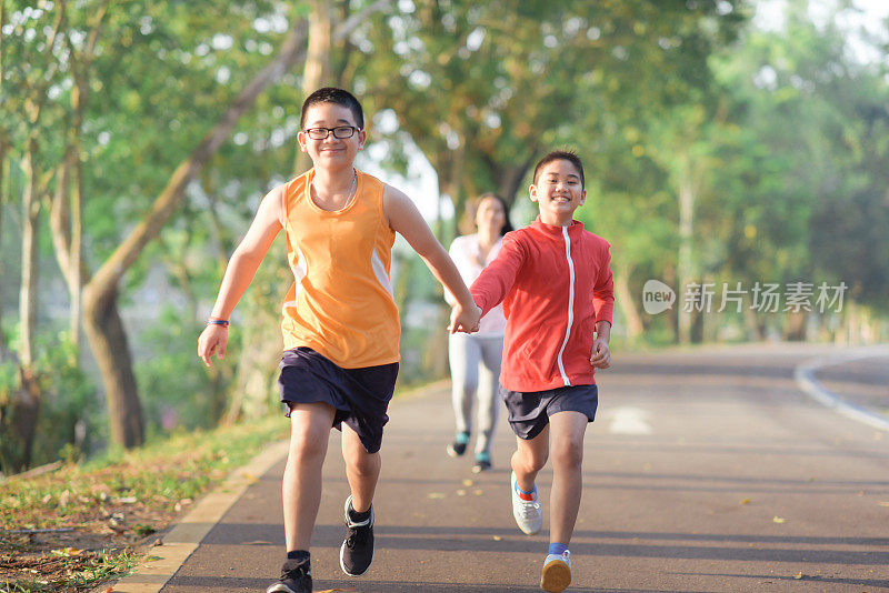 家庭运动快乐活跃的母亲和孩子在户外慢跑，在森林里跑步