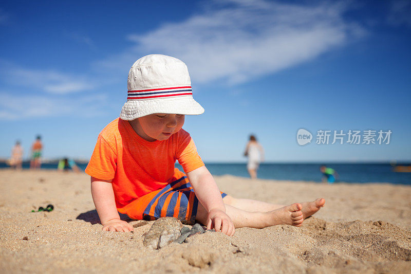 小男孩在沙滩上玩石头和沙子