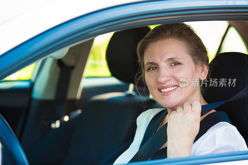 美丽，微笑，快乐，迷人的女人在白色的车里系着安全带